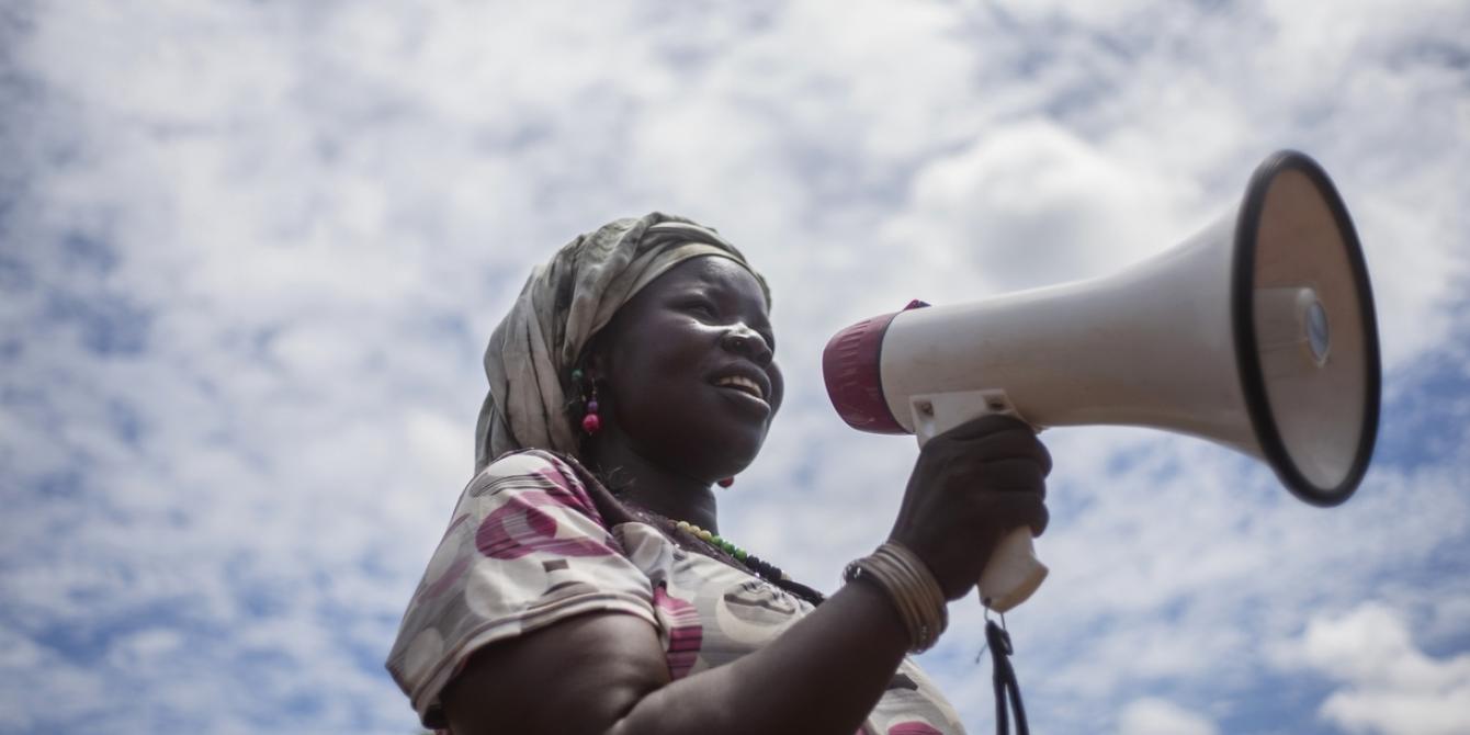 Sarah, the chairperson of a handicrafts group in Bidibidi refugee setttlement, uses a microphone to call women to join her group. Photo:Kieran Doherty/Oxfam Sarah, the chairperson of a handicrafts group in Bidibidi refugee setttlement, uses a microphone to call women to join her group. Photo:Kieran Doherty/Oxfam